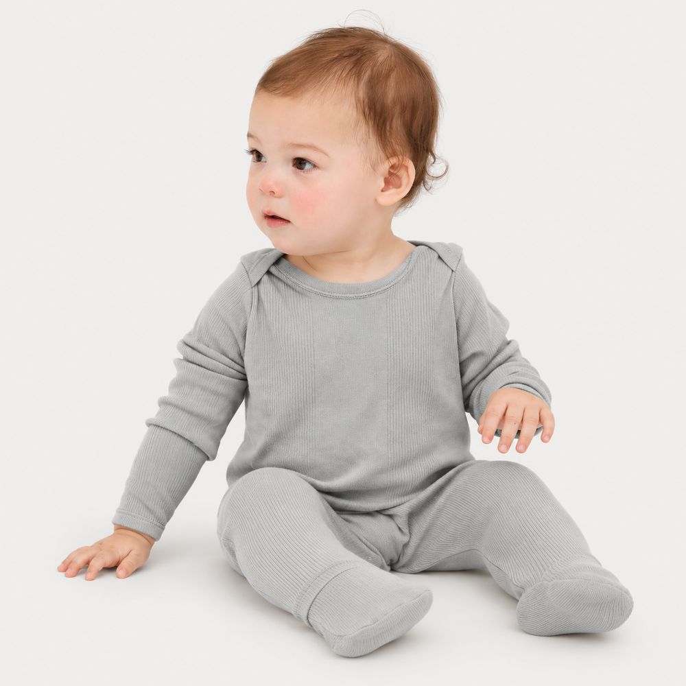 Baby sitting in soft PAIGELAUREN Variegated Rib Footie Pajama. Gray