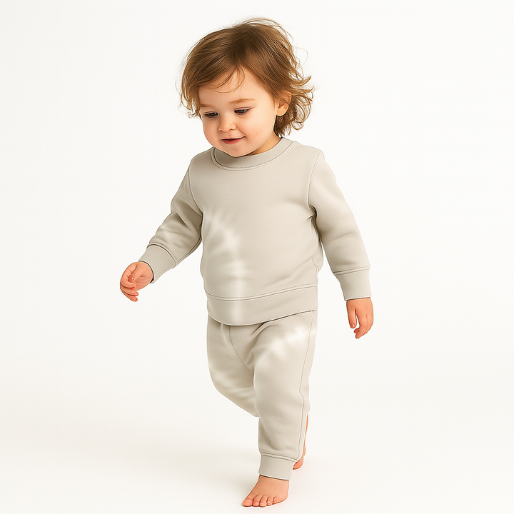 Child wearing a light gray sweatshirt and pants on a white background