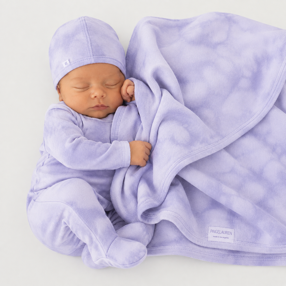 Newborn wearing Lavender Marble Brushed Hacci romper and beanie while snuggling with matching blanket