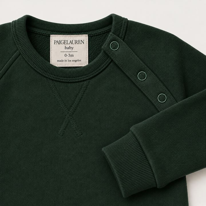 Close-up of the shoulder snap opening on the PAIGELAUREN Fleece Sweatshirt Raglan Romper. Dark Green