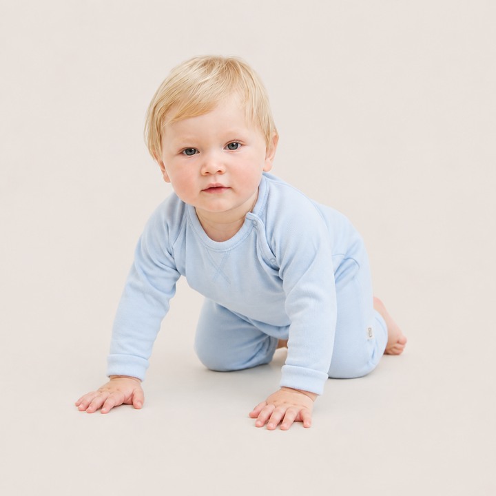 Baby crawling while wearing the PAIGELAUREN Fleece Sweatshirt Raglan Romper in Light Blue