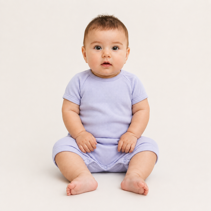 Baby sitting while wearing the PAIGELAUREN Garment Dye Ribbed Shortall Onesie. Lavender