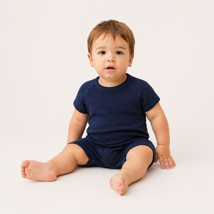 Baby sitting while wearing the PAIGELAUREN Garment Dye Ribbed Shortall Onesie. Navy
