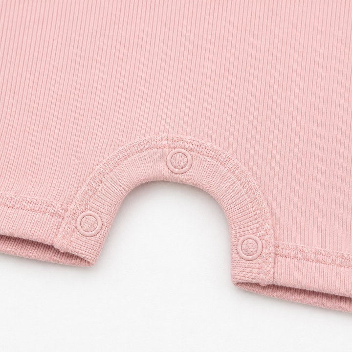 Close-up of the color-matched ring snaps and reinforced snap inseam on the PAIGELAUREN Garment Dye Ribbed Shortall Onesie