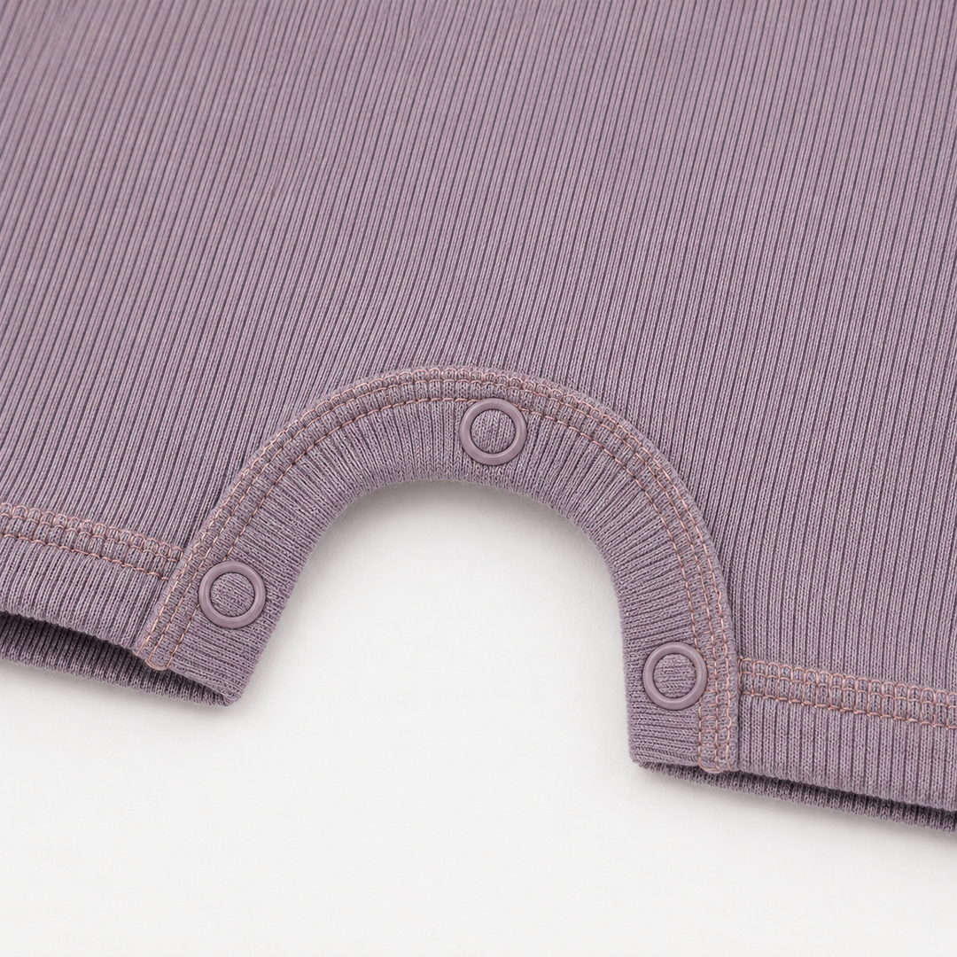 Close-up of the color-matched ring snaps and reinforced snap inseam on the PAIGELAUREN Garment Dye Ribbed Shortall Onesie