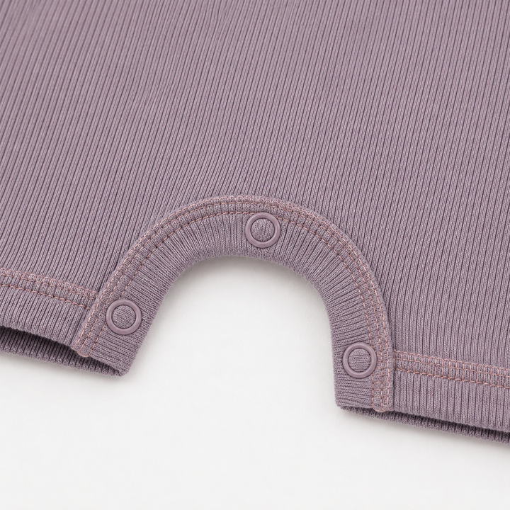 Close-up of the color-matched ring snaps and reinforced snap inseam on the PAIGELAUREN Garment Dye Ribbed Shortall Onesie