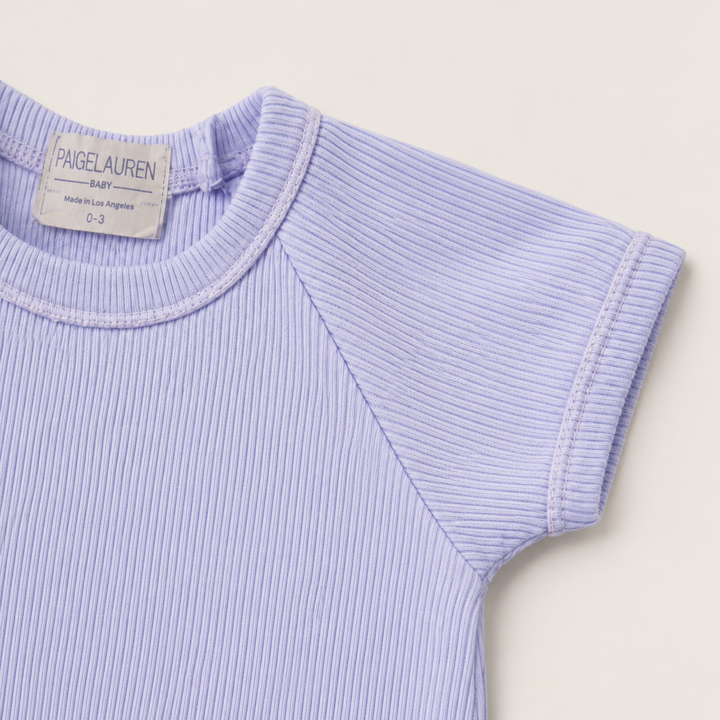 Detail of the raglan sleeve, cuff, and premium rib knit on the PAIGELAUREN Garment Dye Ribbed Shortall Onesie. Lavender
