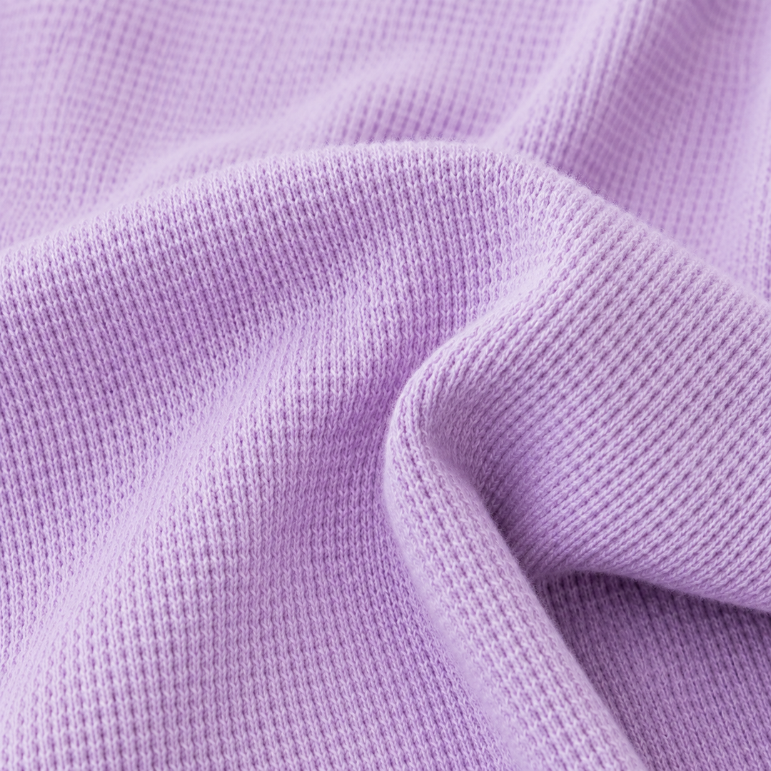 Close-up of soft garment dyed thermal knit fabric in lilac showing premium texture