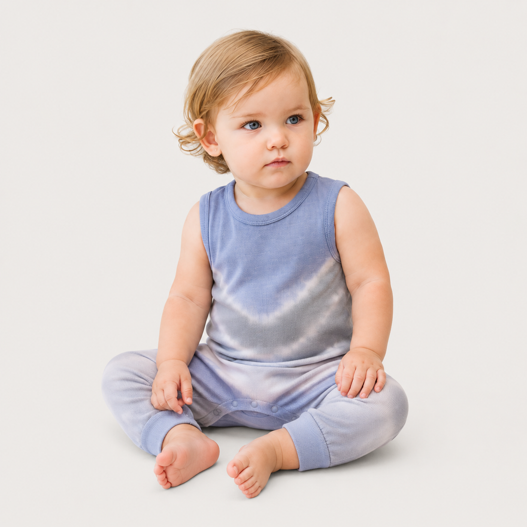 Baby sitting in the PAIGELAUREN Gray Baby Rib Tie Dye Tank Overall with hand-dyed tie dye finish