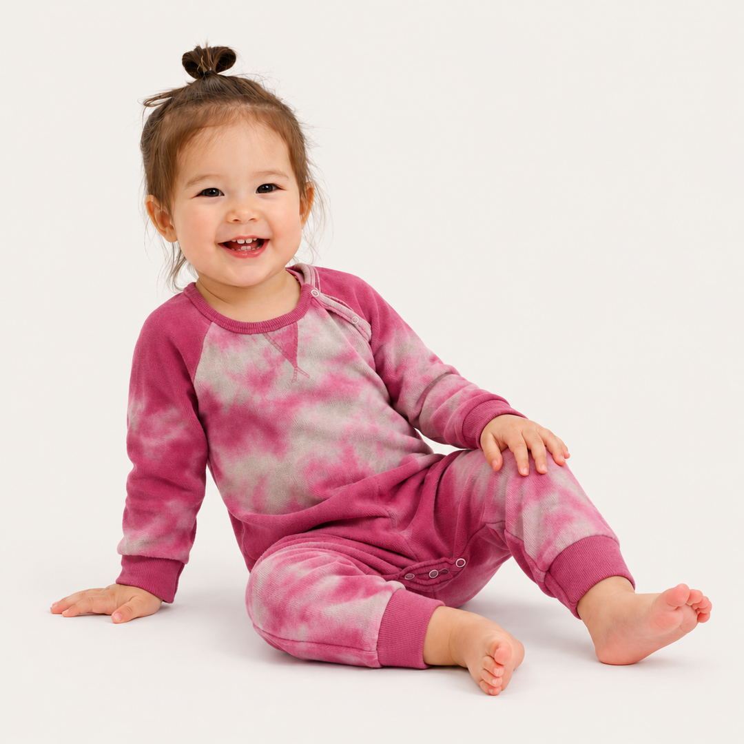 Baby wearing the PAIGELAUREN Heathered Fleece Marble Sweatshirt Romper in Pink Marble while sitting
