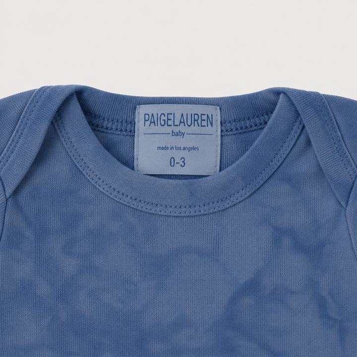 Lap shoulder neckline detail on PAIGELAUREN Blue Marble Brushed Hacci Footed Romper
