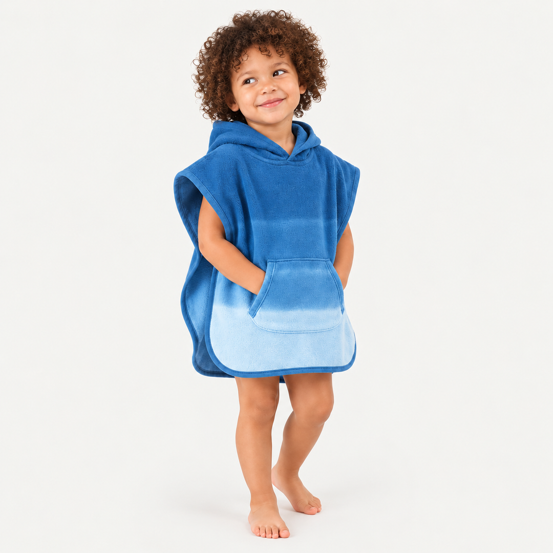 Curly-haired toddler wearing blue ombré hooded terry poncho with kangaroo pocket