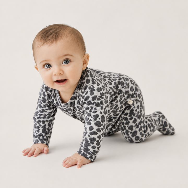 Baby crawling in PAIGELAUREN black and white animal print Brushed Hacci Footed Pajama