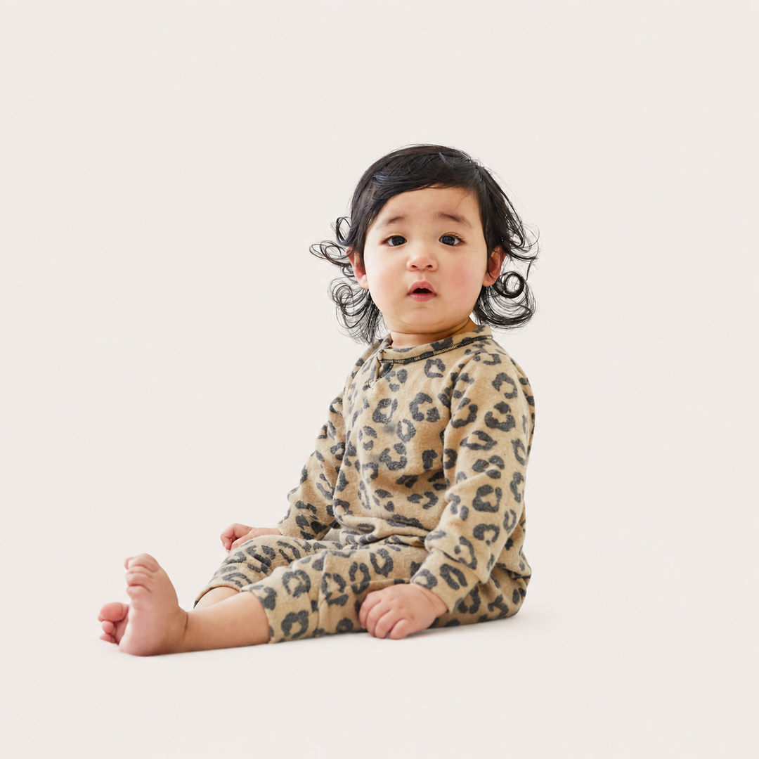 Baby sitting while wearing the PAIGELAUREN Brushed Hacci Animal Henley Romper.