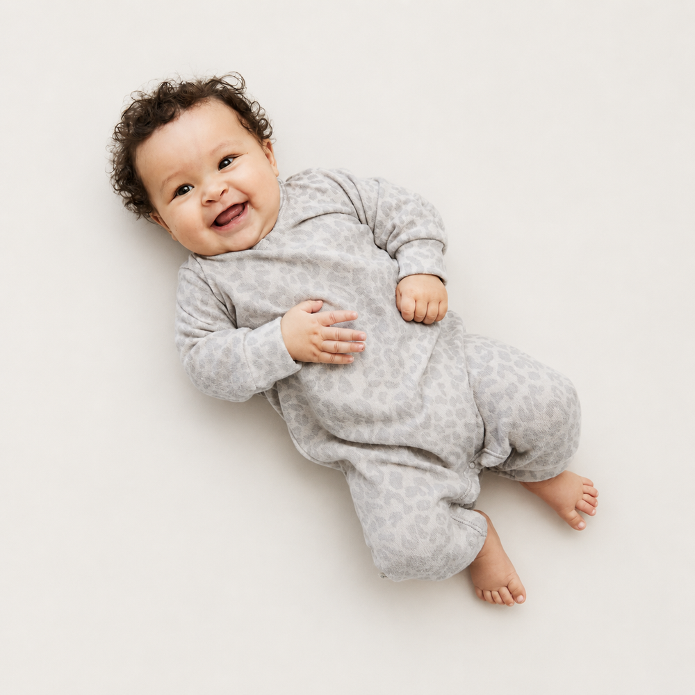 Baby wearing the PAIGELAUREN Brushed Hacci Animal Henley Romper in tonal animal print.
