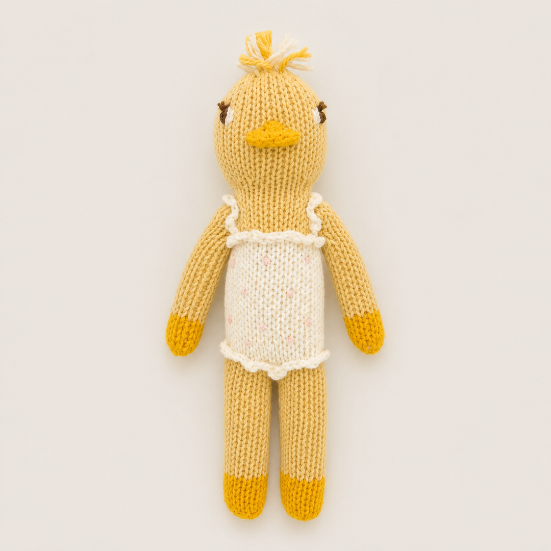 Hand knit duck baby toy in yellow with cream ruffle romper and embroidered details