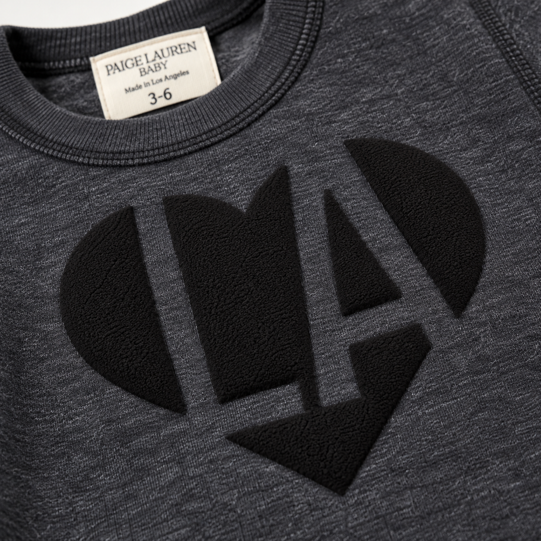 Close-up of black puffed LA heart graphic on PAIGELAUREN Heathered Black fleece