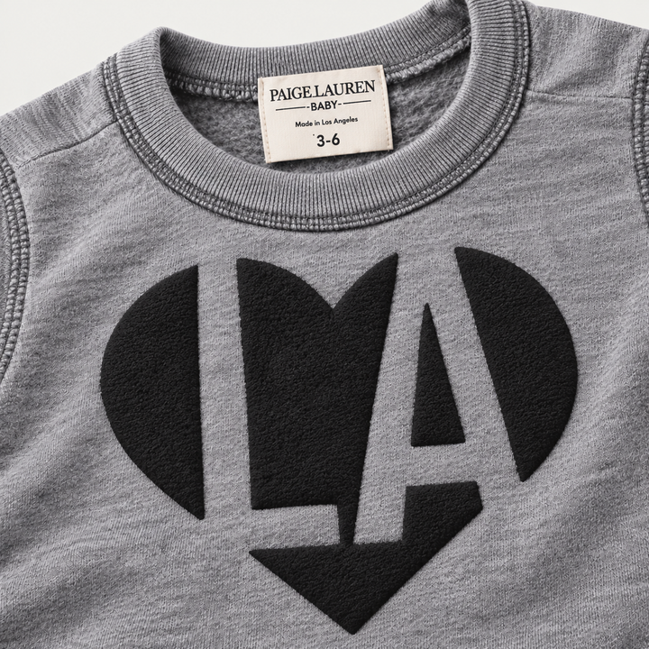 Close-up of black puffed LA heart graphic on PAIGELAUREN Heathered Gray fleece