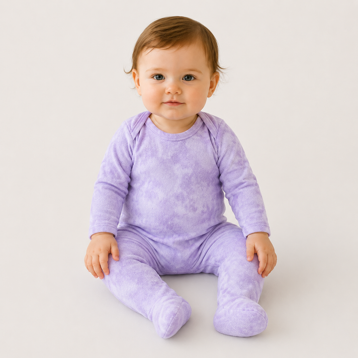 Baby sitting in PAIGELAUREN lavender Marble Brushed Hacci Footed Pajama