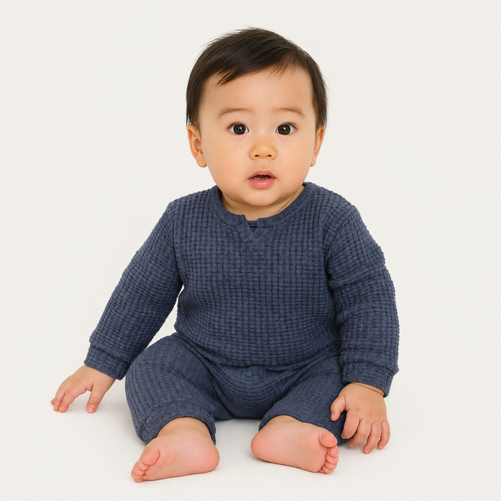 Baby wearing the PAIGELAUREN Navy Chunky Thermal Romper in a minimalist studio.