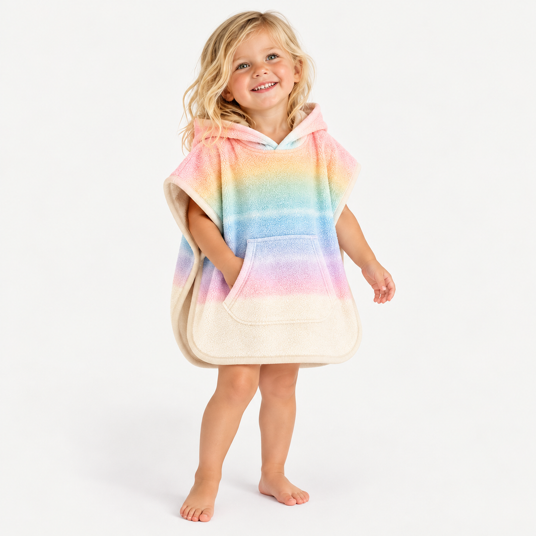 Beachy blonde toddler wearing PAIGELAUREN Pastel Rainbow Ombré Hooded Terry Poncho