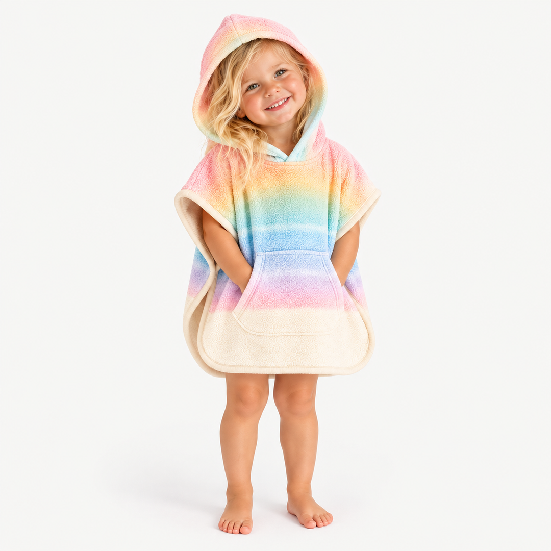 Blonde toddler smiling with hood up in pastel rainbow loop terry poncho