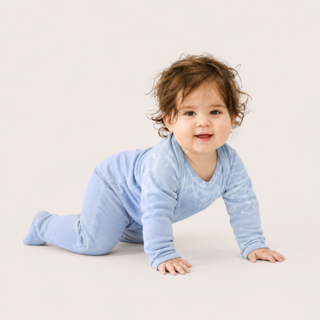 Baby crawling in PAIGELAUREN gray and blue Rib Tie Dye Footed Pajama
