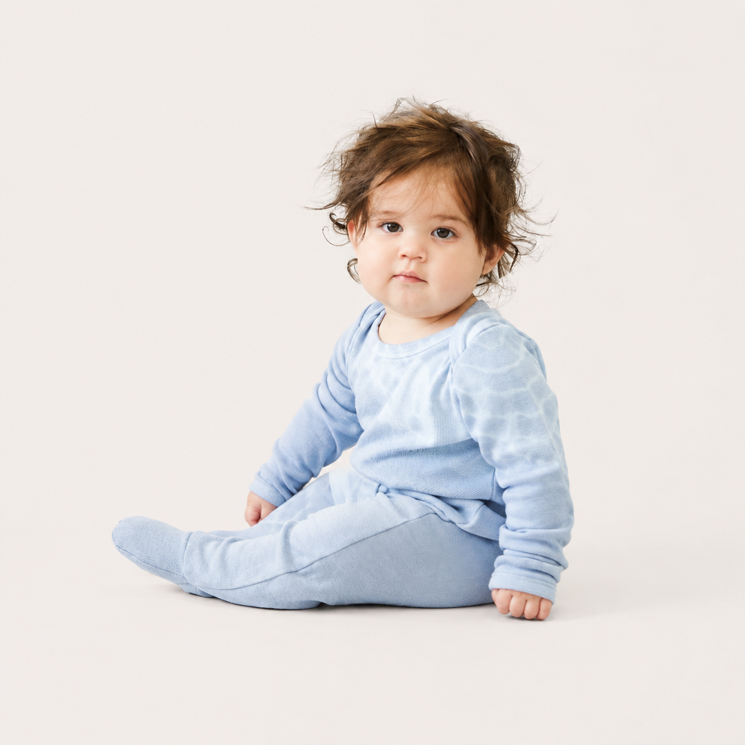 Baby sitting in PAIGELAUREN gray and blue Rib Tie Dye Footed Pajama