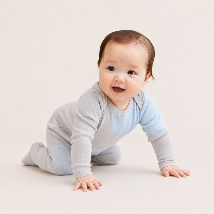 Baby crawling in PAIGELAUREN oat and blue Rib Tie Dye Footed Pajama