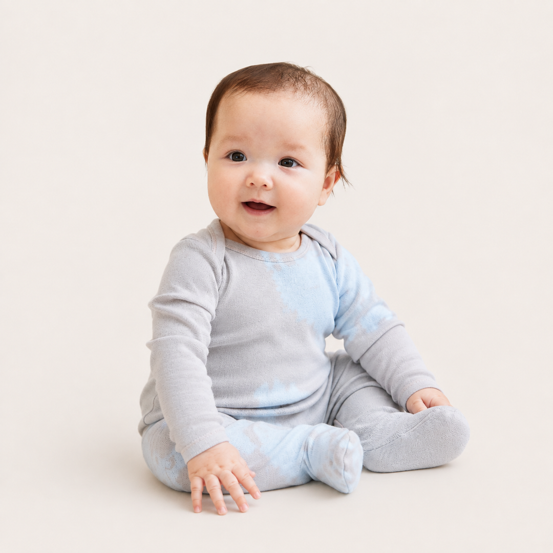 Baby sitting in PAIGELAUREN oat and blue Rib Tie Dye Footed Pajama