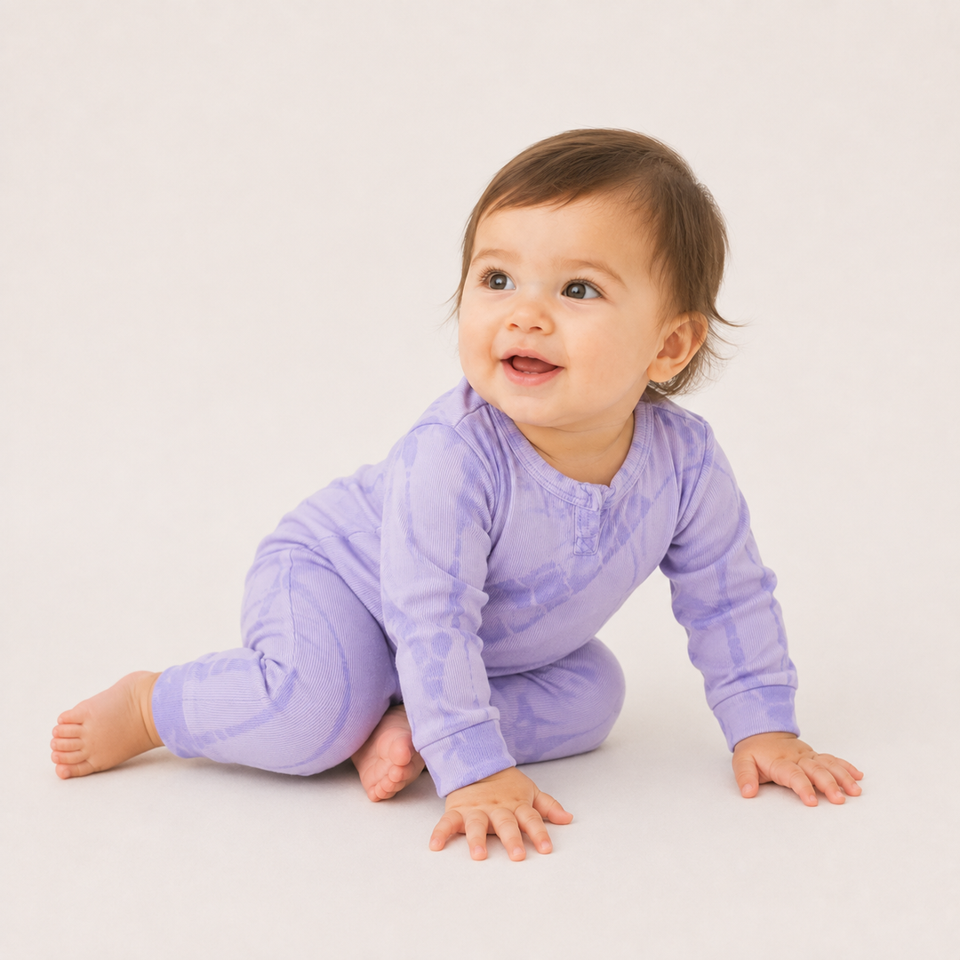 Crawling baby wearing the PAIGELAUREN Ribbed Lavender Tonal Tie Dye Henley Romper.