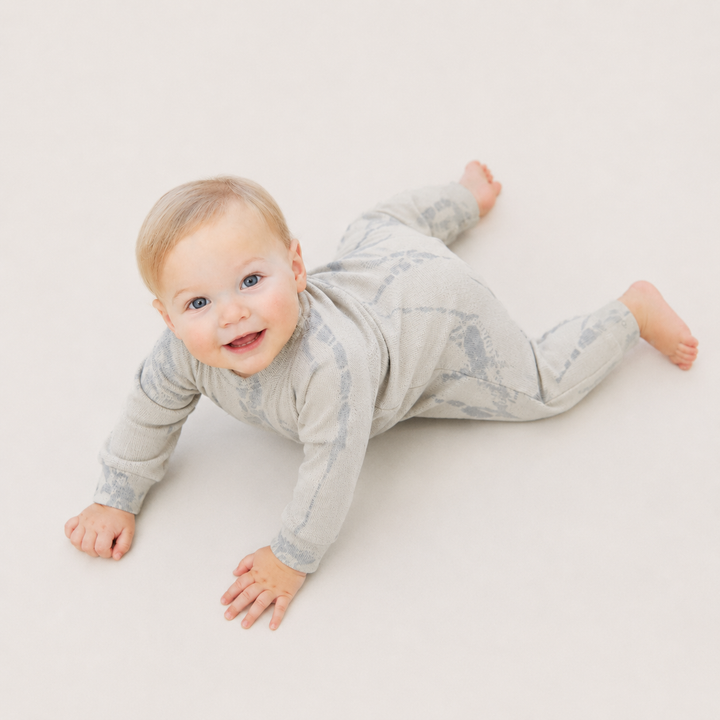 Crawling baby wearing the PAIGELAUREN Ribbed Oat Tonal Tie Dye Henley Romper.