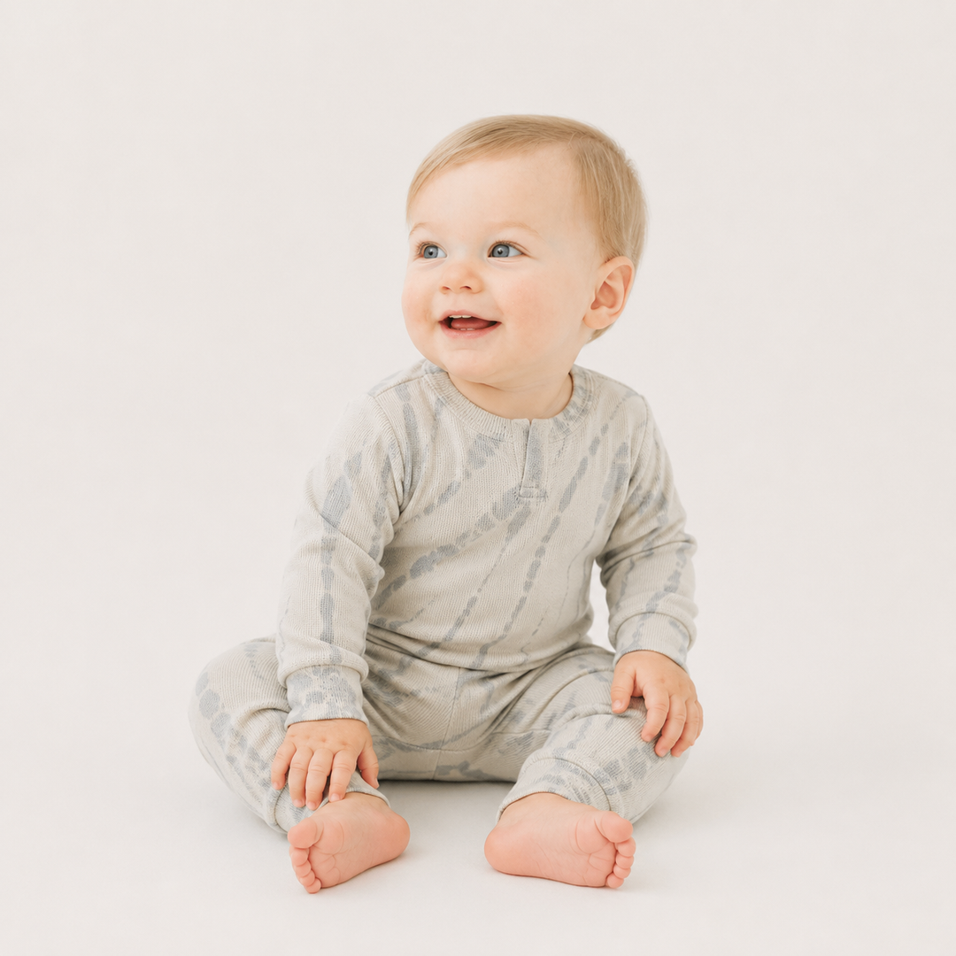 Baby wearing the PAIGELAUREN Ribbed Oat Tonal Tie Dye Henley Romper.