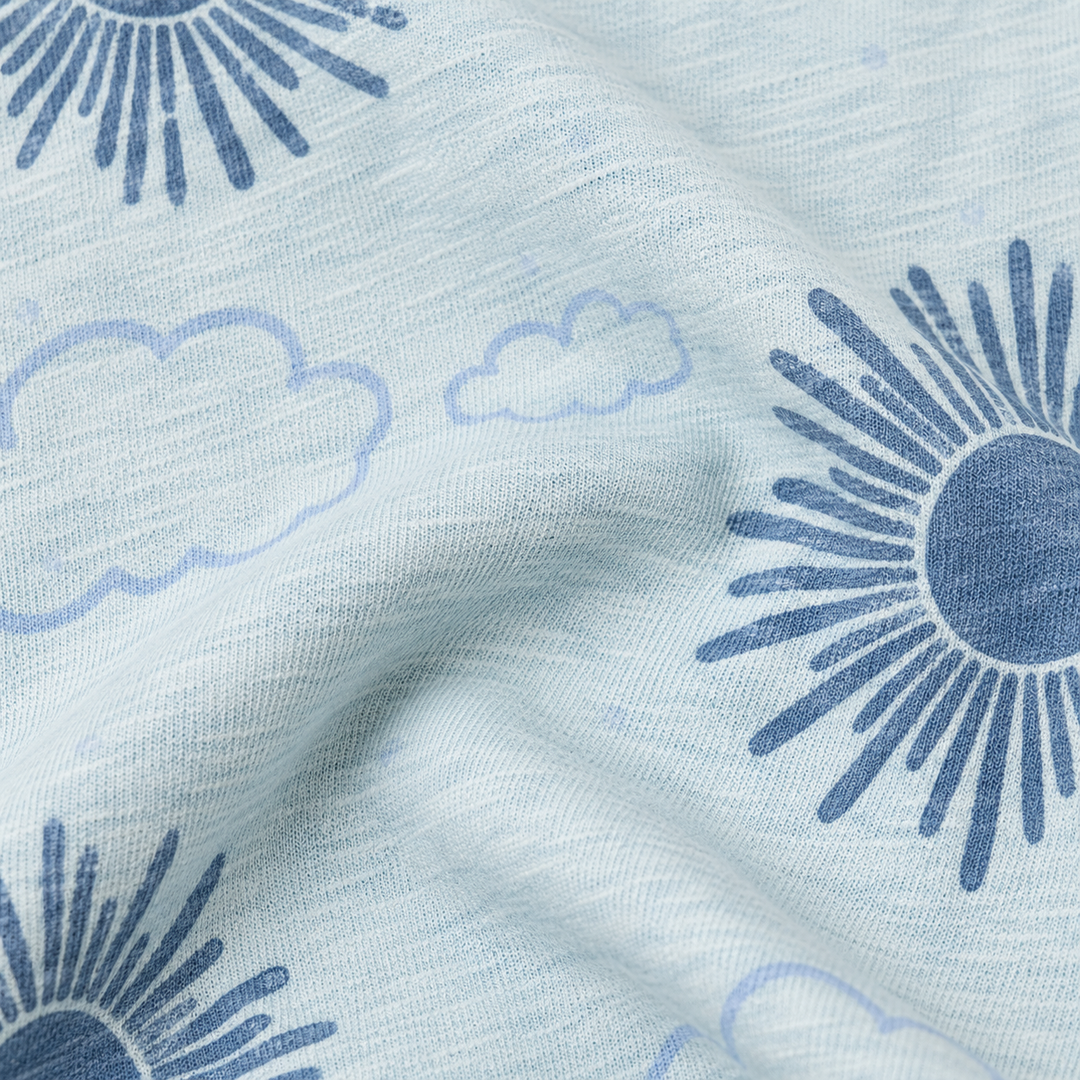 Close-up of PAIGELAUREN light blue slub fabric with sun and cloud print