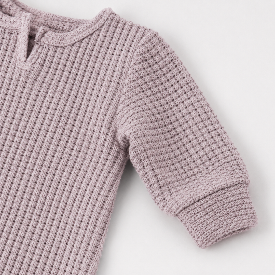 Beige matching sleeve cuff and chunky thermal texture on the PAIGELAUREN romper.