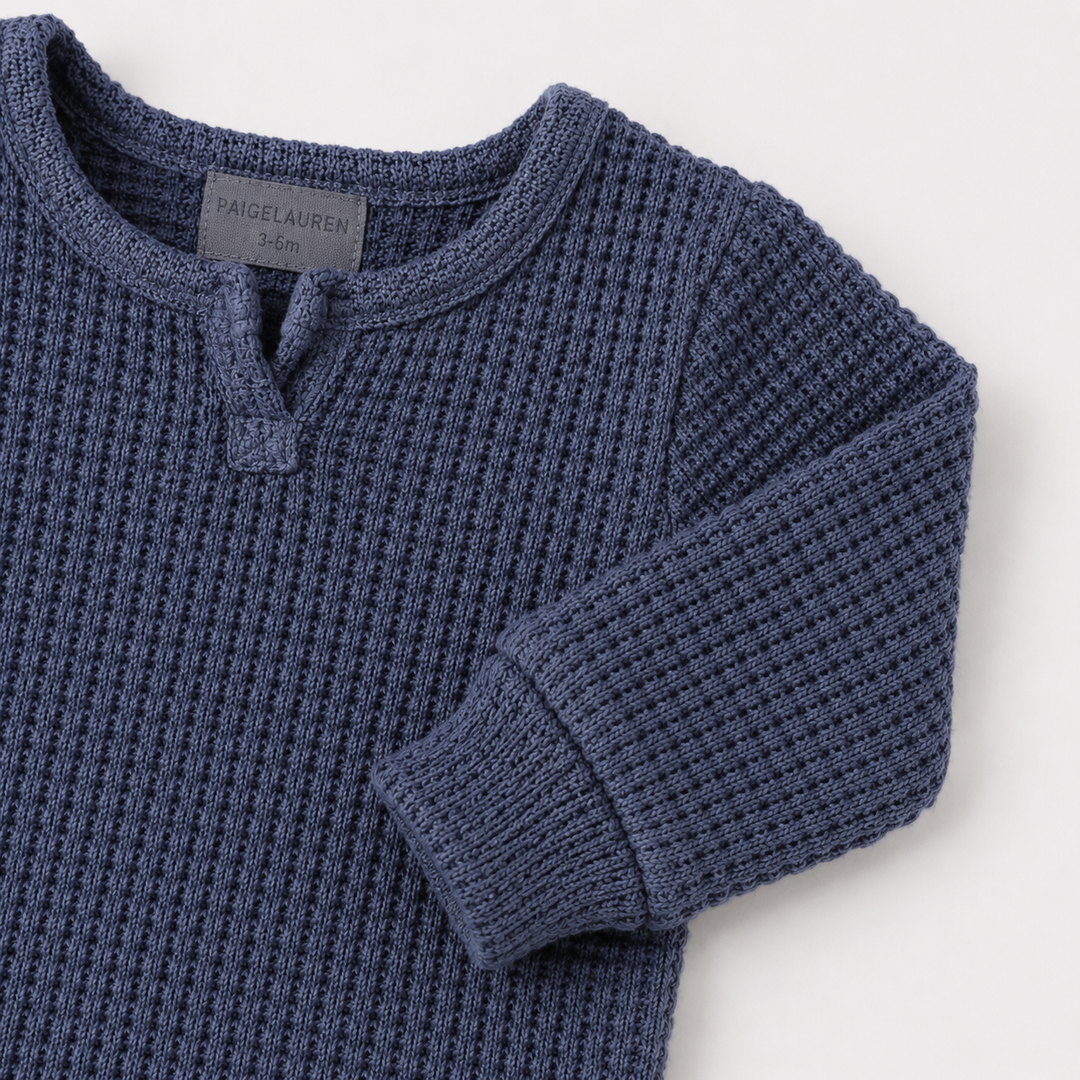 Navy matching sleeve cuff and chunky thermal texture on the PAIGELAUREN romper.