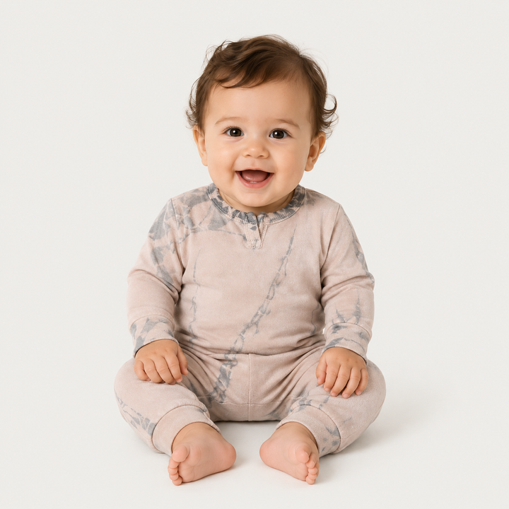 Baby wearing the PAIGELAUREN Beige tonal dyed romper in a minimalist studio.