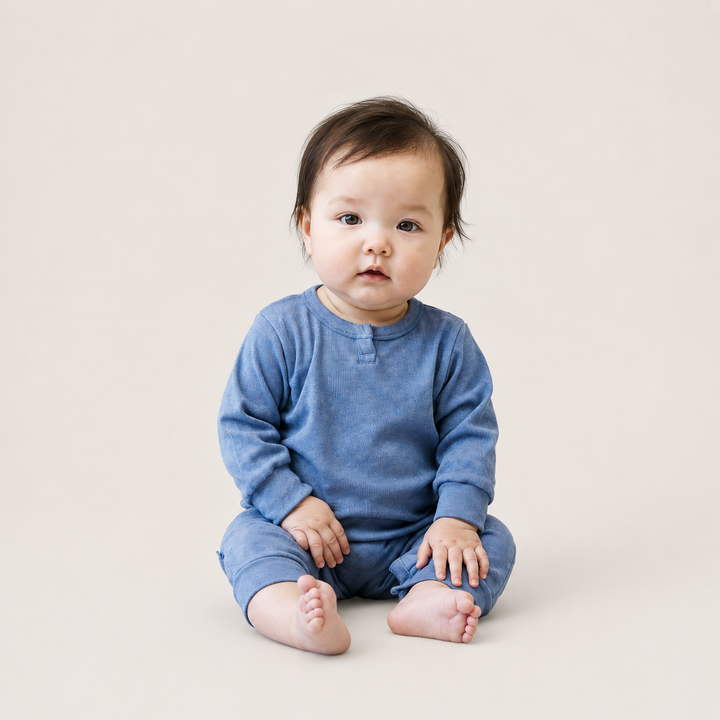 Baby wearing the PAIGELAUREN Rib Marble Henley Romper in soft blue marble wash