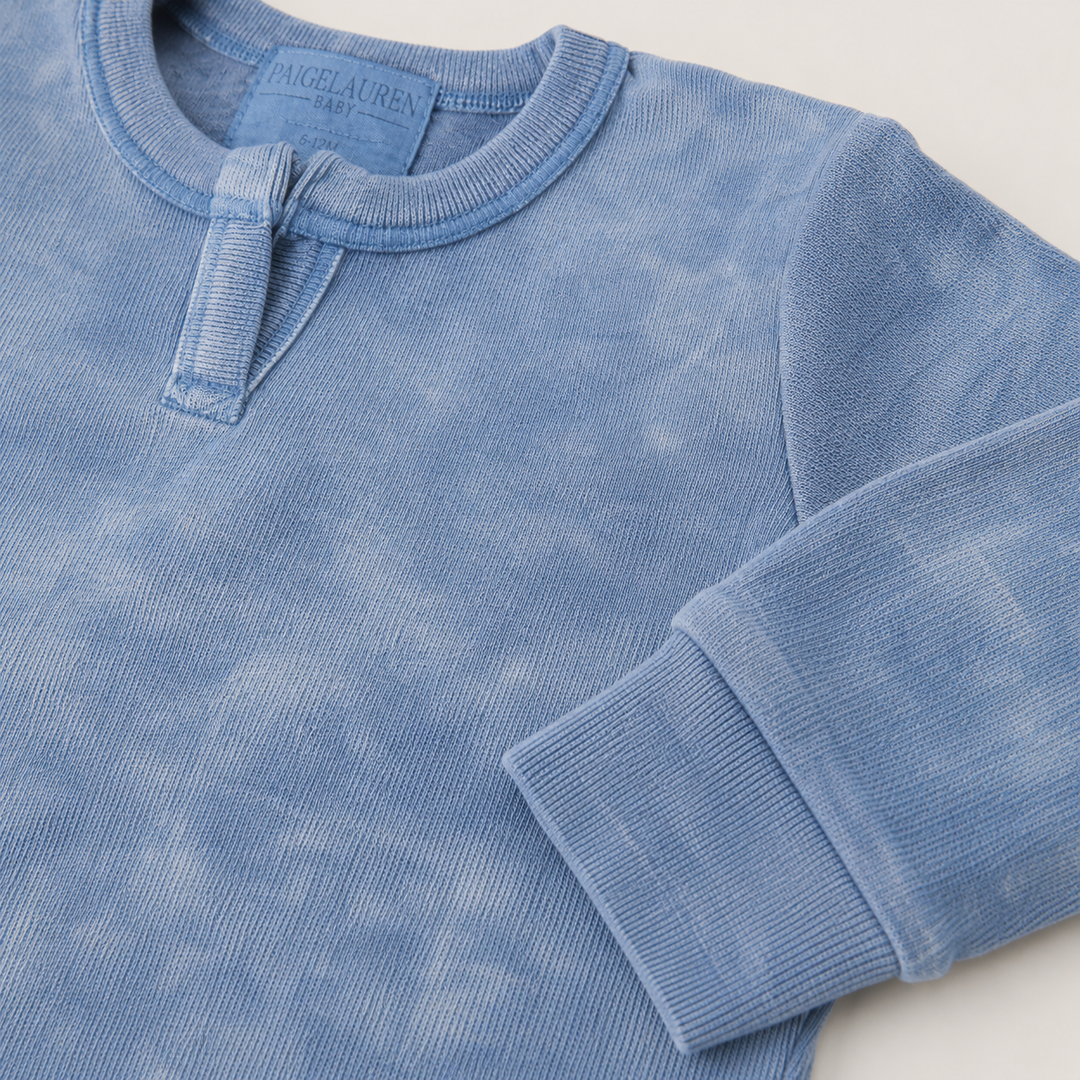 Close-up of the Henley neckline and rib sleeve detail on the PAIGELAUREN Rib Marble Henley Romper. Blue Marble