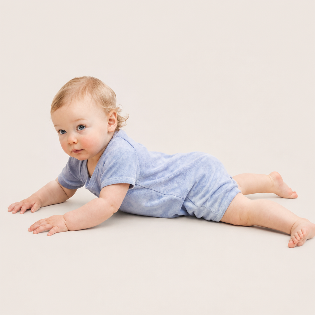 Baby crawling in the PAIGELAUREN Light Blue Marble Rib Shortall Onesie