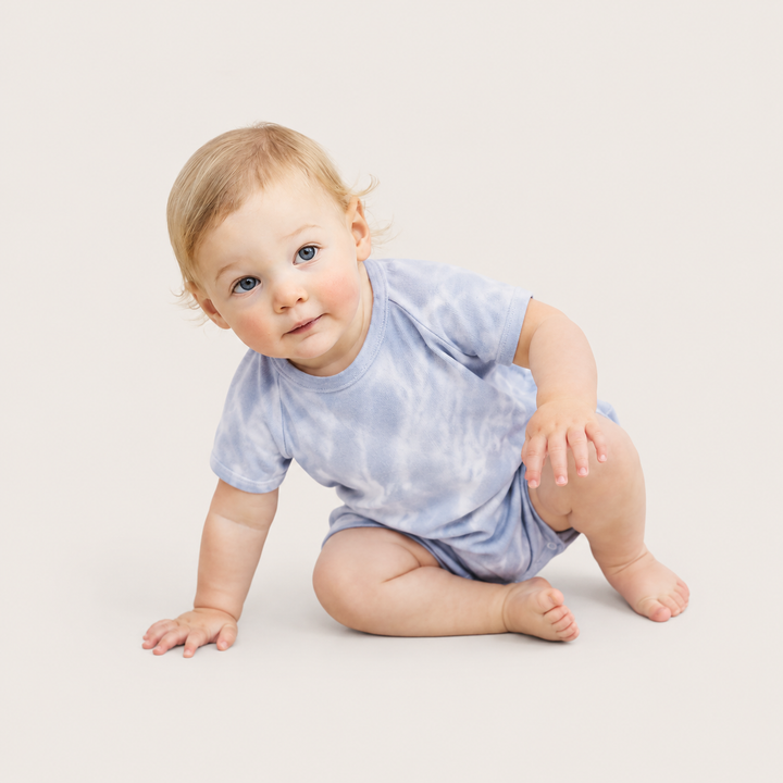 Baby sitting while wearing the PAIGELAUREN Light Blue Marble Rib Shortall Onesie