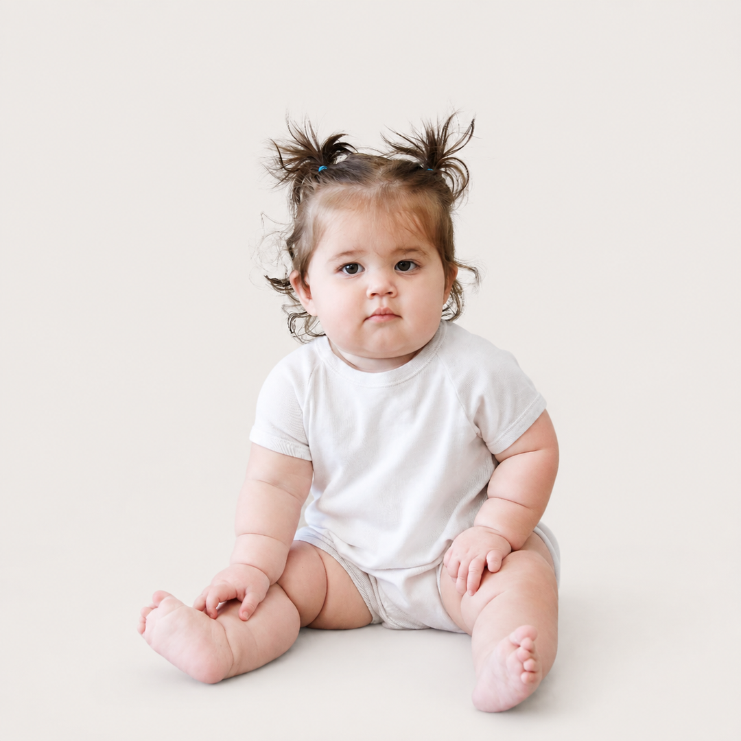 Baby sitting while wearing the PAIGELAUREN Light Gray Marble Rib Shortall Onesie