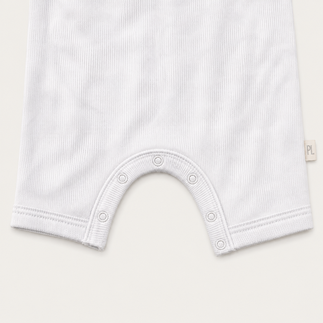 Close-up of the color-matched ring snap closure and reinforced crotch construction on the PAIGELAUREN Rib Marble Shortall Onesie