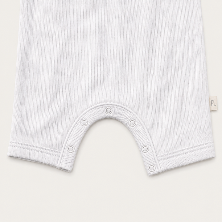 Close-up of the color-matched ring snap closure and reinforced crotch construction on the PAIGELAUREN Rib Marble Shortall Onesie
