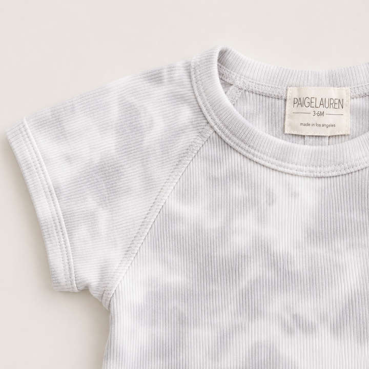 Close-up of the ribbed crew neckline and raglan sleeve construction on the PAIGELAUREN Rib Marble Shortall Onesie